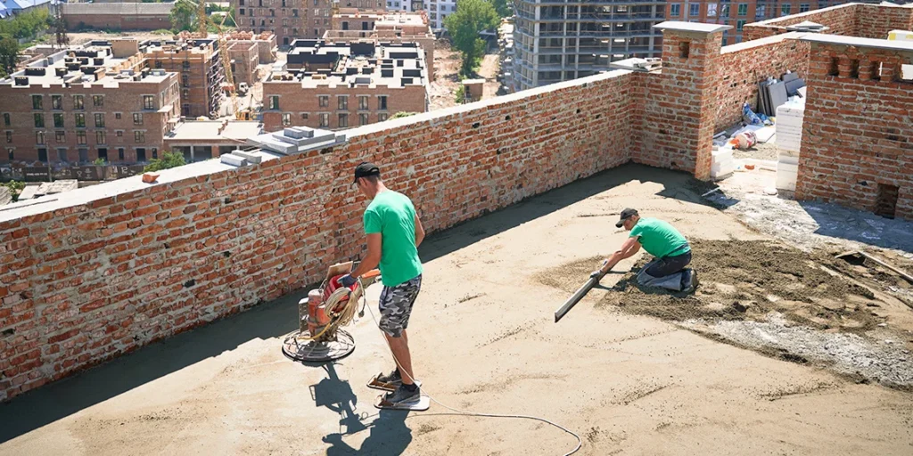 Two men applying cement for brick pointing while working on a roof.
