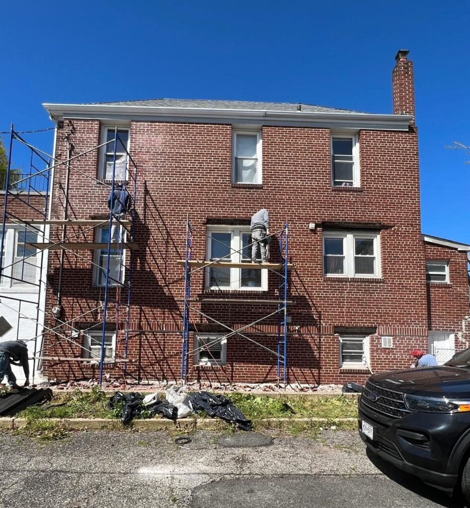 A parked car in front of a brick house under scaffolding, showcasing a brick pointing service in New York City.