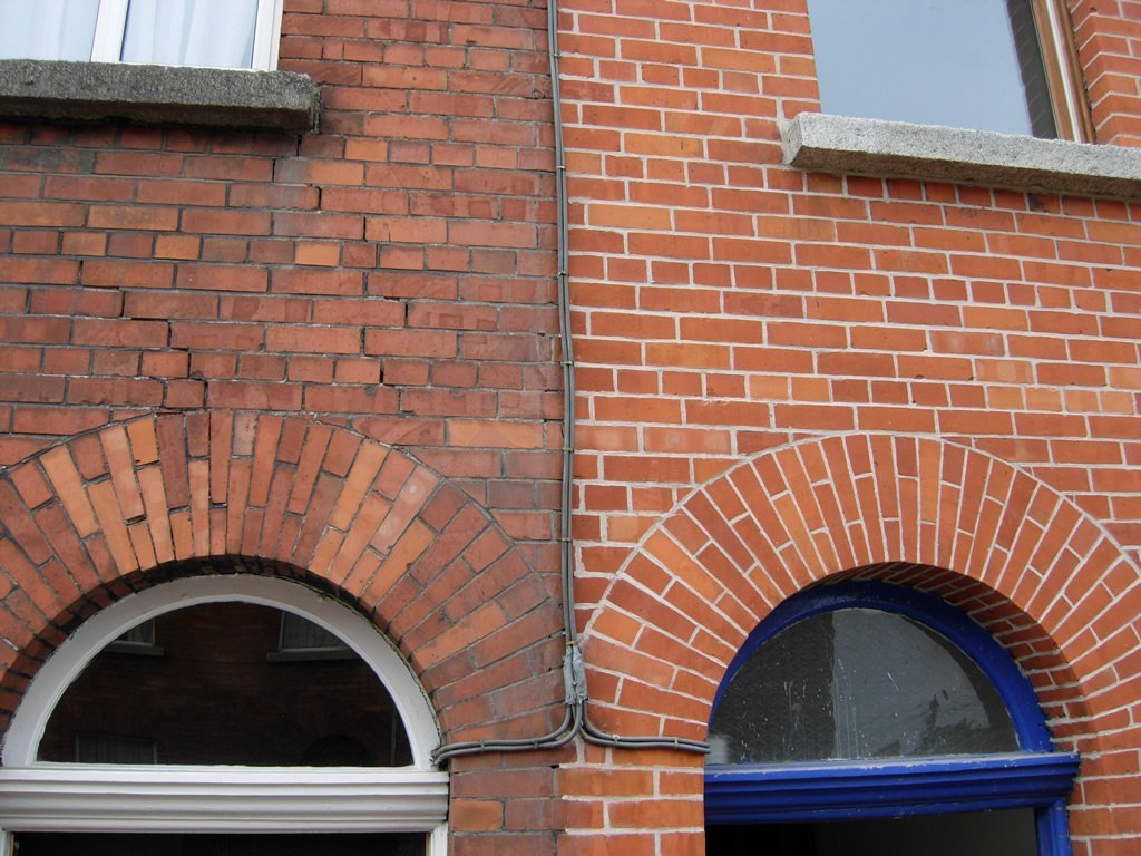 Side-by-side view of two brick walls showing different textures and a noticeable crack on the left structure's wall.