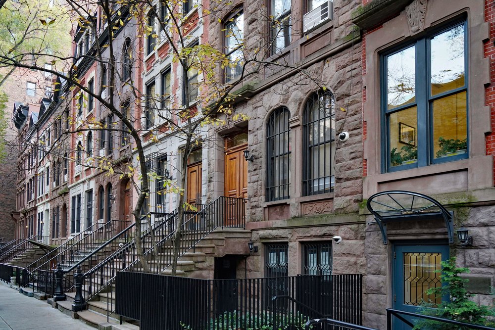 Brownstone restoration on historic NYC row houses showing repaired brickwork, matched mortar colors, and preserved architectural details.