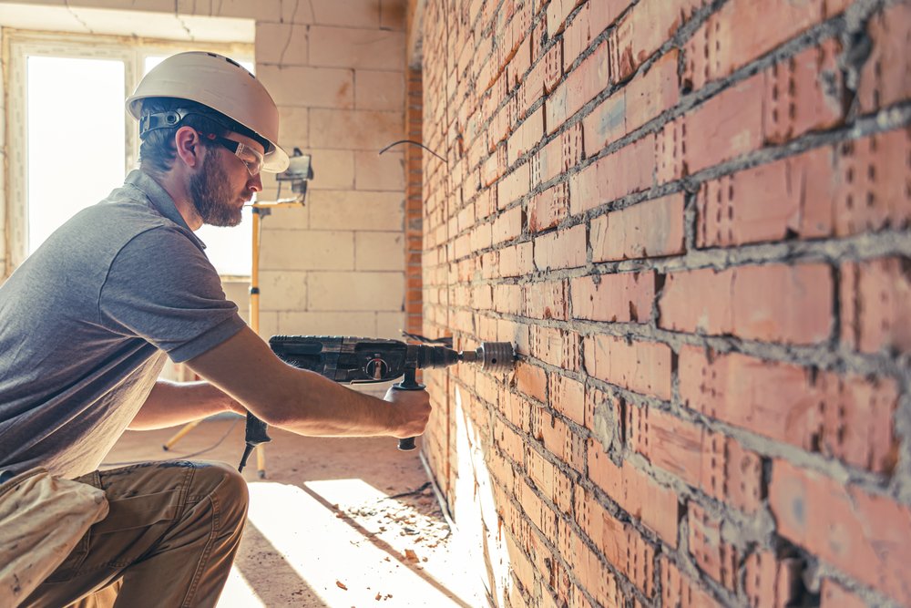 Facade Repointing.The builder works with a drill in working form.