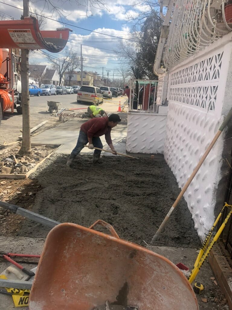 Worker repairing a concrete driveway by resurfacing and smoothing the slab to create a strong, long-lasting surface.