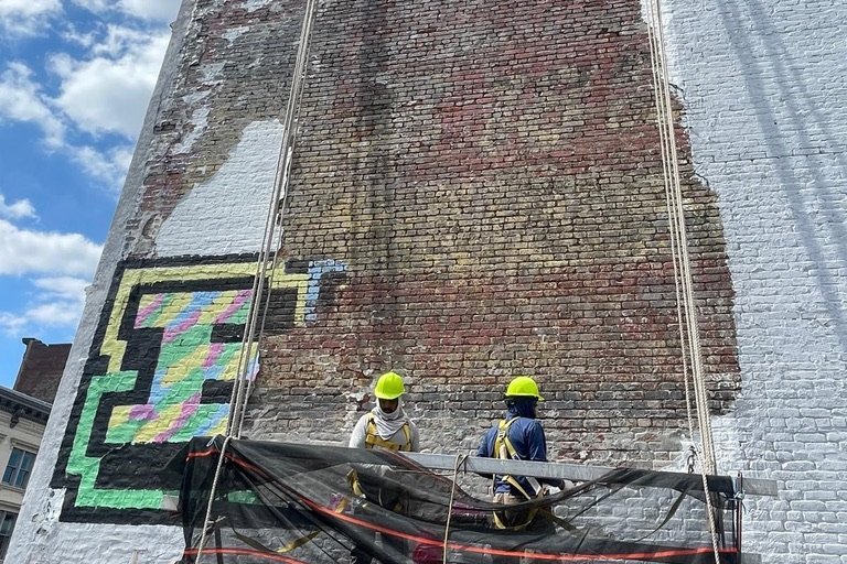 Masons repointing a NYC brick facade from a swing scaffold